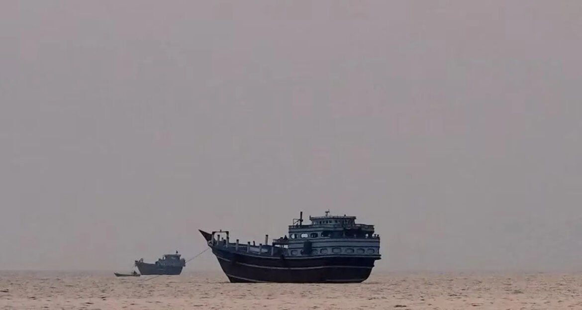 Large blue-and-white ship anchored on a calm sea with a small boat nearby in the hazy horizon at dusk.