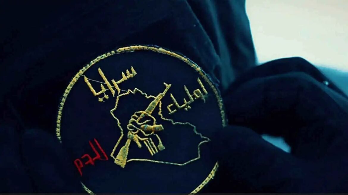Gold-embroidered circular patch showing a raised fist gripping a rifle inside a map-like outline on dark fabric; red lettering is partially visible nearby.