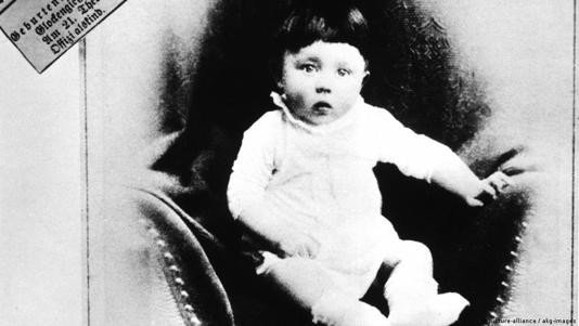 Black and white Photo of a Baby in a White Outfit Sitting in an Upholstered Chair Looking at the Camera  Aleumumnews