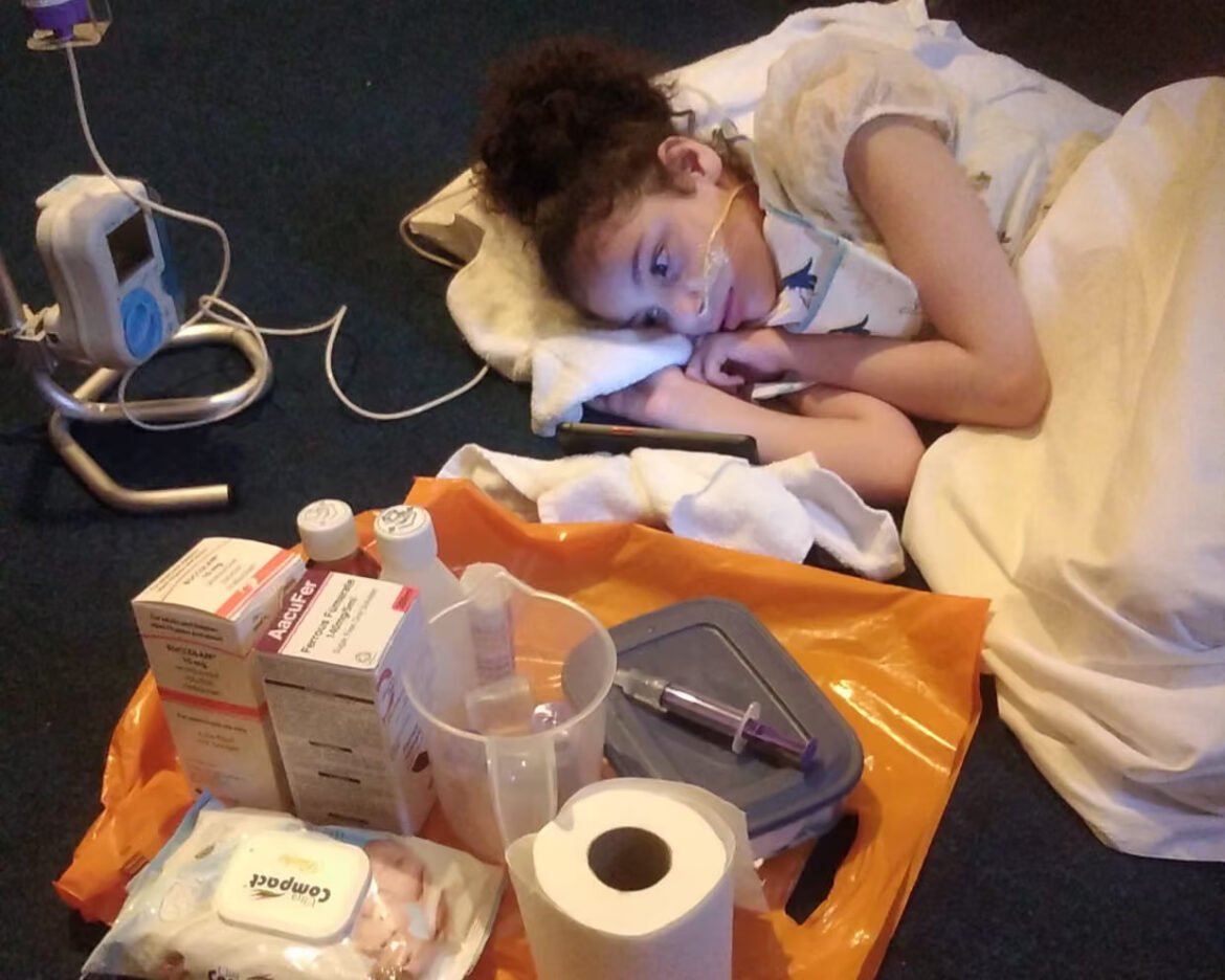 Child patient asleep on a hospital bed with oxygen tubing and a pillow, surrounded by medical supplies and equipment nearby.