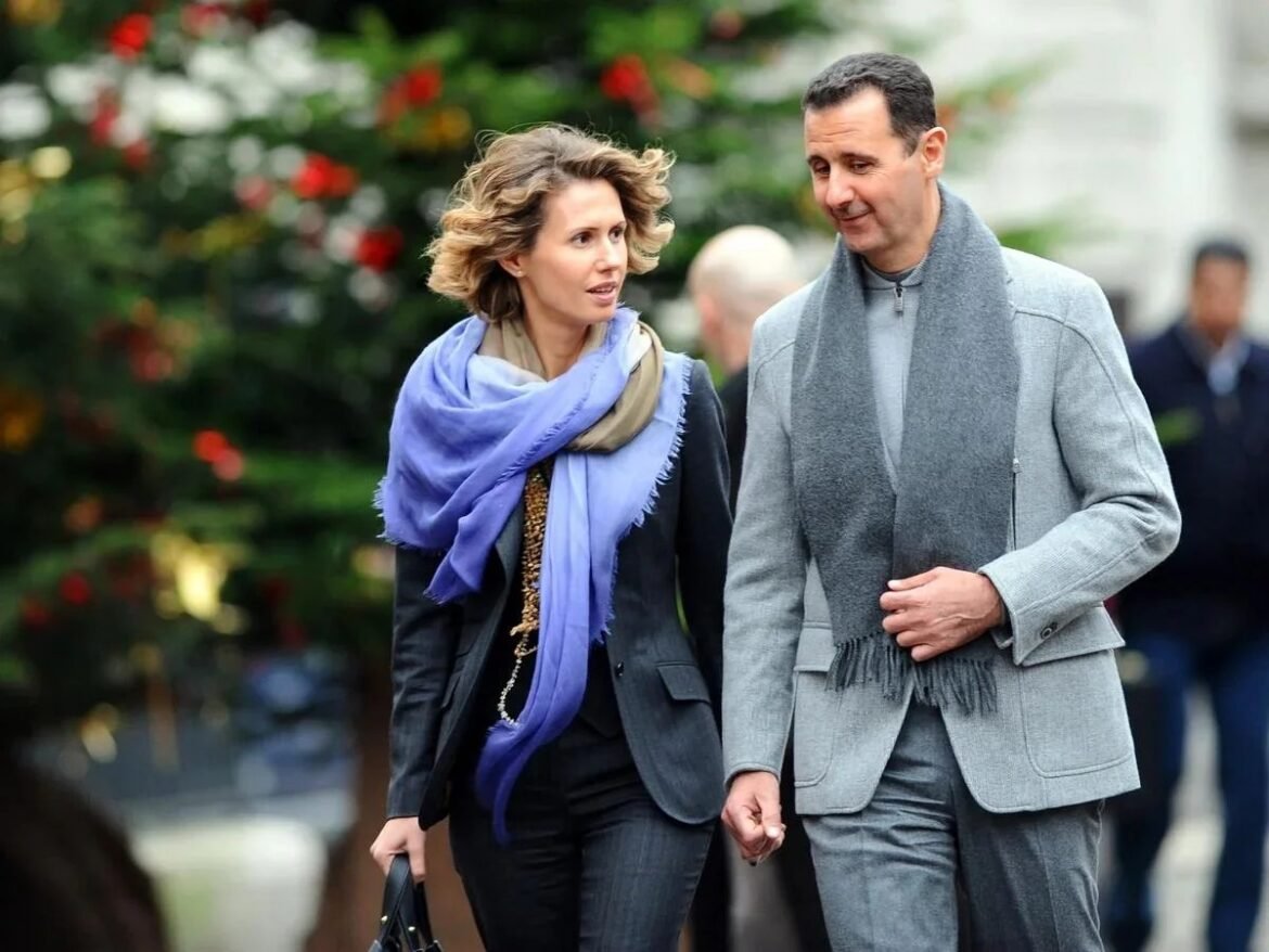 Couple walking hand in hand outdoors, dressed in coats with scarves, chatting as they stroll on a city sidewalk.