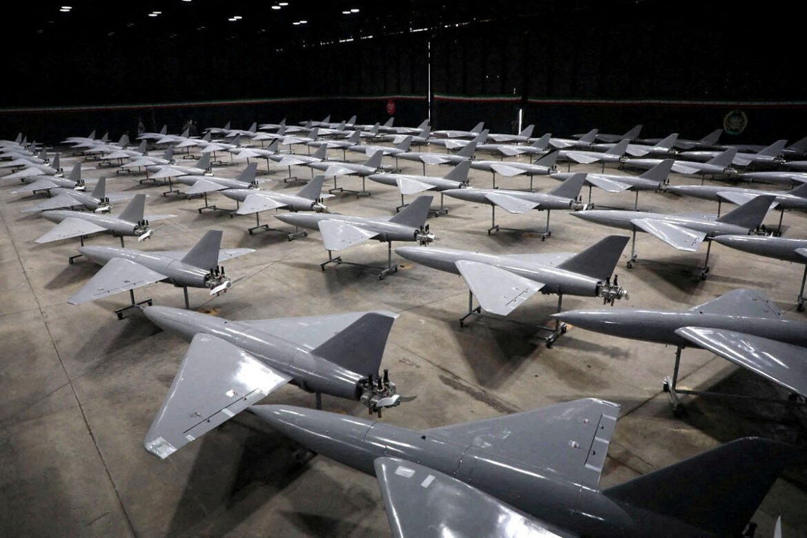Dozens of gray jet aircraft on wheeled stands arranged in neat rows inside a large hangar.