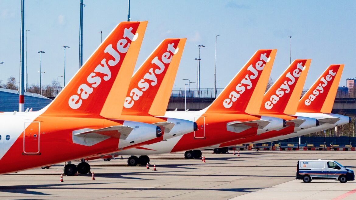Several easyJet airplanes parked at an airport tarmac with bright orange tails lined up.