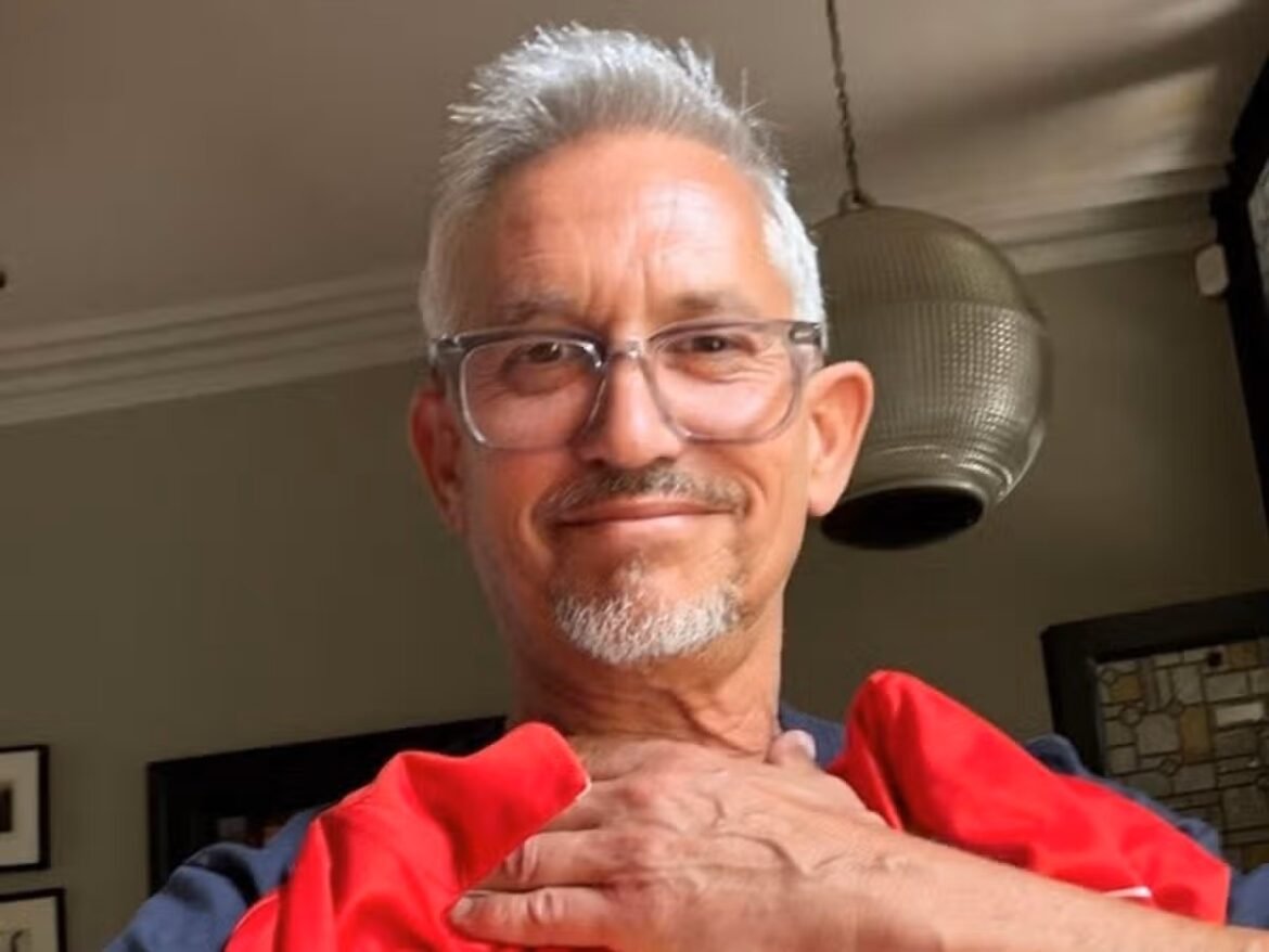Smiling older man with gray hair and glasses, wearing a red jacket draped over his shoulders indoors.