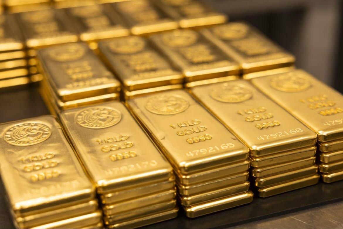 Stacks of shiny gold bullion bars arranged in a display, reflecting light in a vault setting.