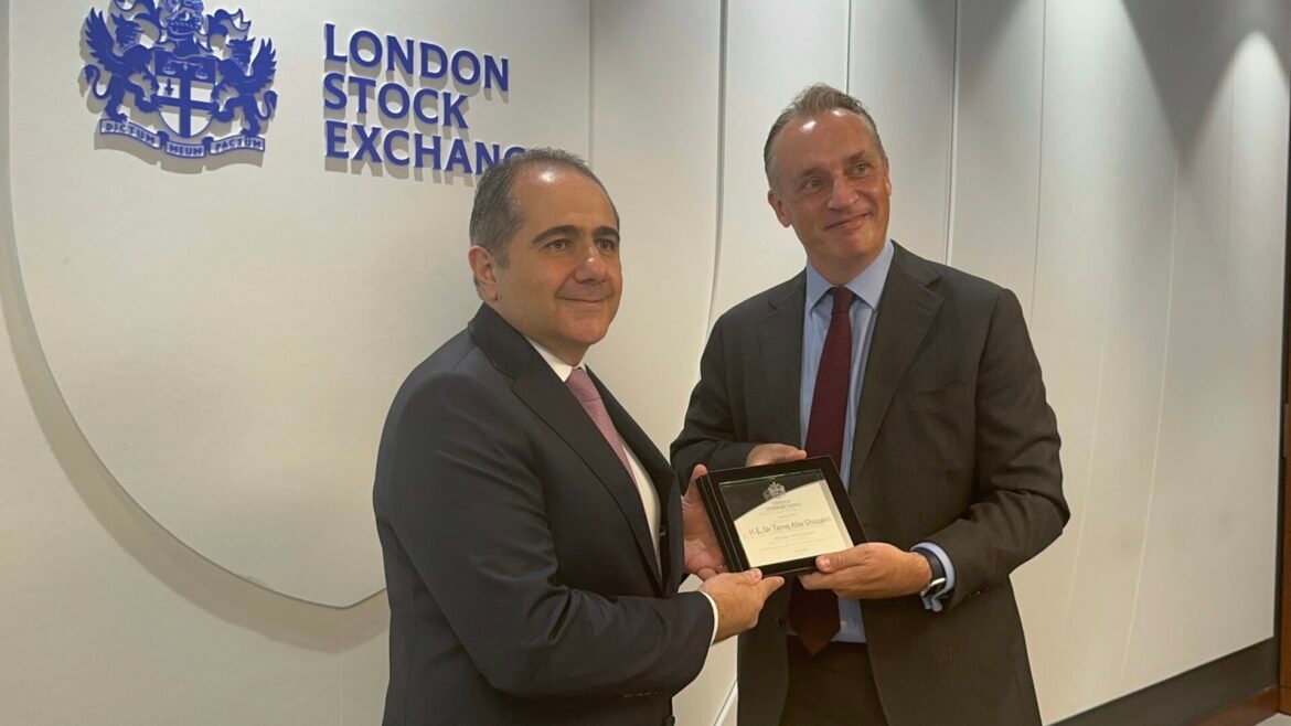 Two businessmen in dark suits exchange a framed award near the London Stock Exchange logo.