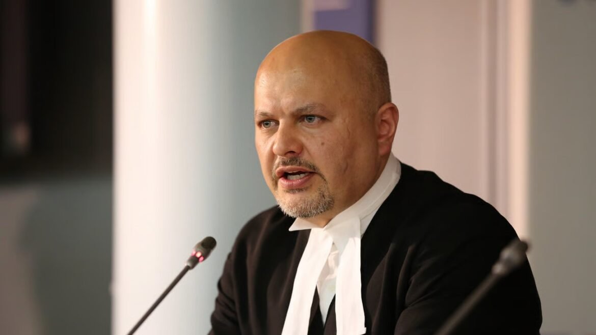 Man in a black suit and white collar speaks into a microphone at a conference panel.