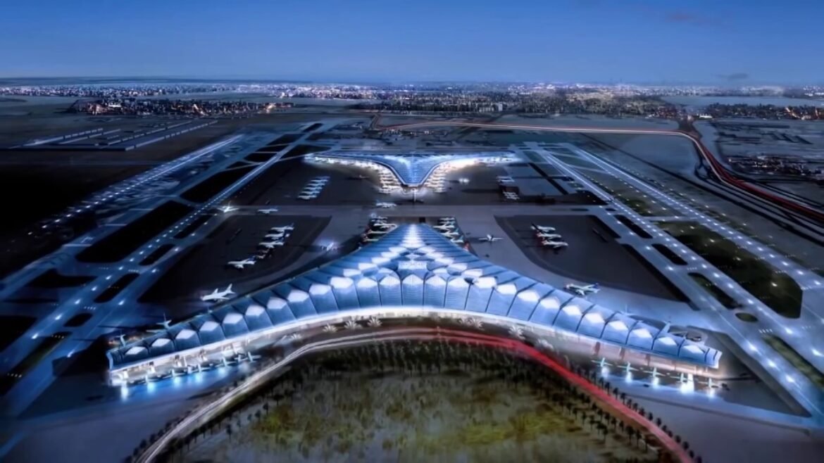 Aerial view of a futuristic airport with blue sail-shaped terminal roofs and parked airplanes at gates.