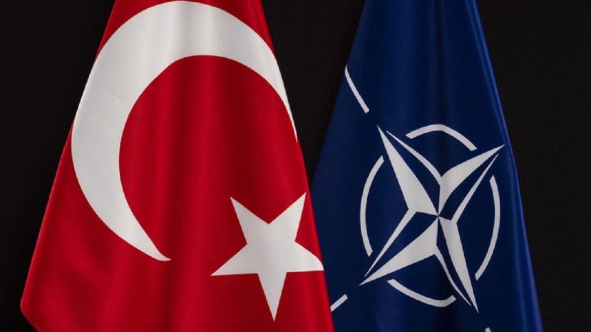 Turkish flag beside the NATO flag against a dark background