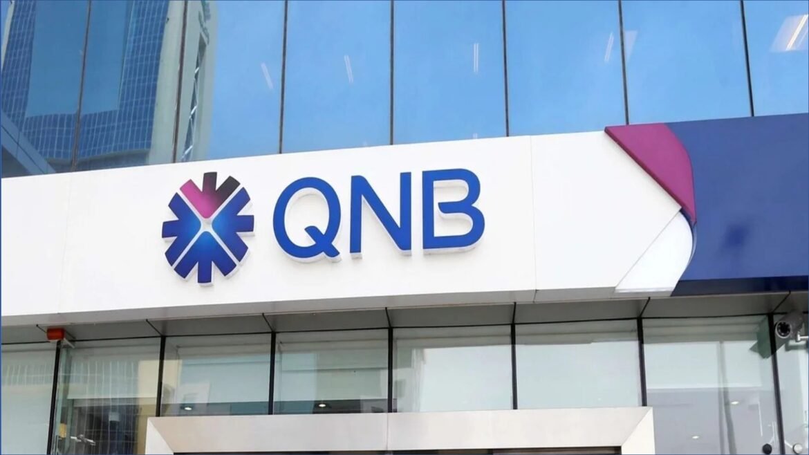 Signage for QNB bank on a modern glass building, showing the blue QNB letters and starburst logo on white surface