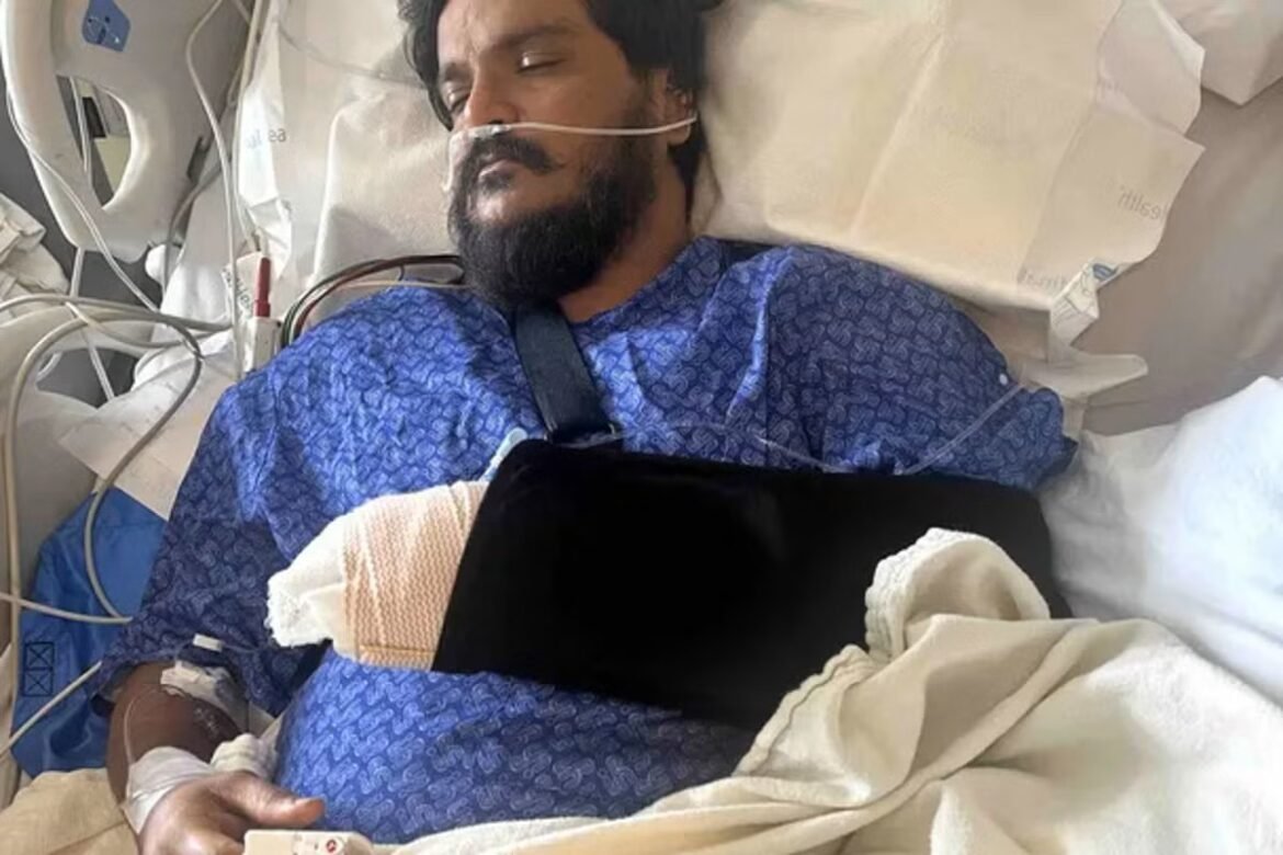 Man in a hospital bed wearing an oxygen mask and blue gown, connected to medical tubing and monitors.