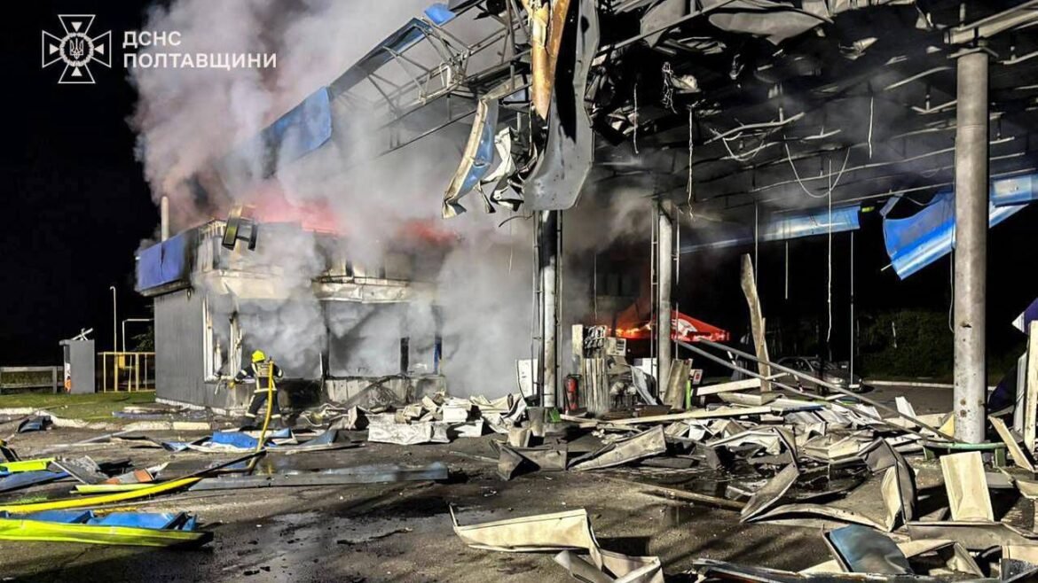 Nighttime scene of a firefighter spraying water at a burning, collapsed industrial building with smoke and scattered debris; emergency services logo in corner (ДСНС Полтавщини).