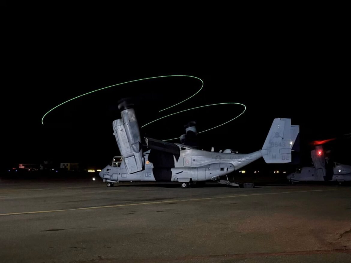 Night scene of a Chinook helicopter on a runway, with bright green rotor-light trails circling above it.