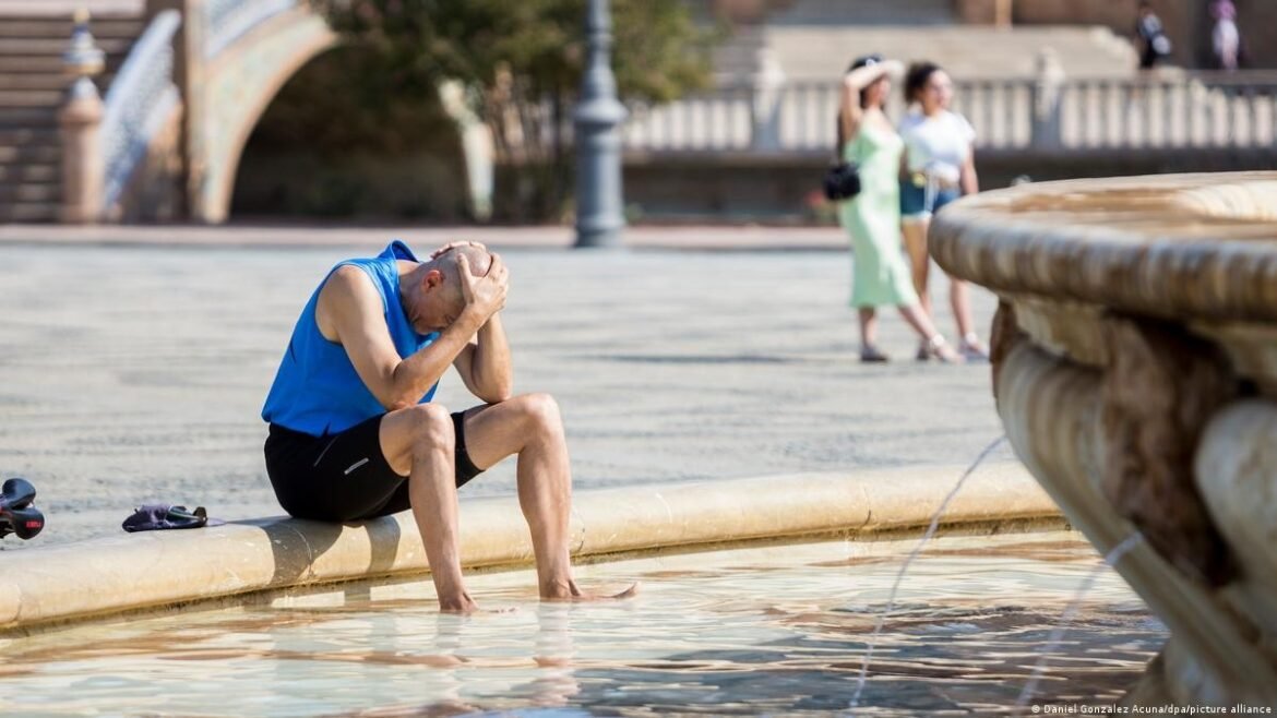 Man in a blue sleeveless shirt sits on the fountain edge with his head in his hands, appearing distressed.