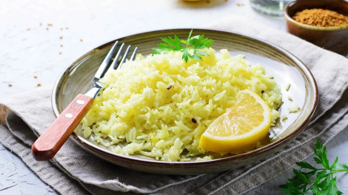 Plate of lemon rice garnished with parsley and a lemon wedge, with a fork resting on the edge of the dish.