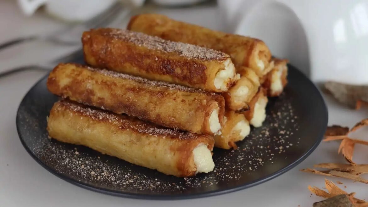 Stack of crispy fried cheese sticks dusted with powdered sugar on a dark plate
