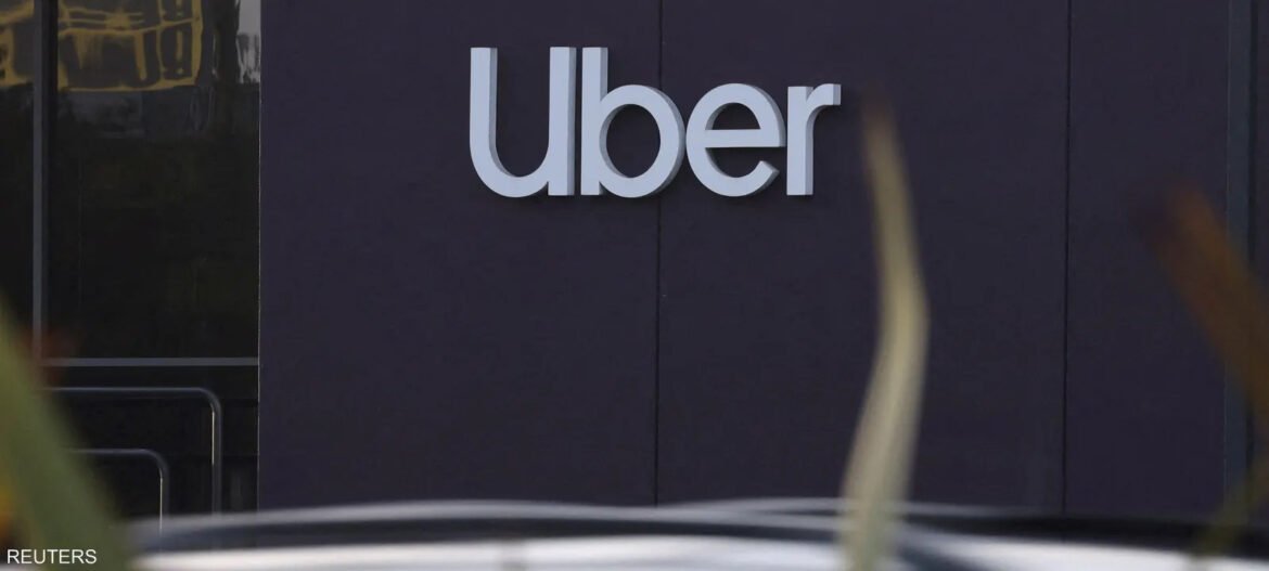 Uber logo mounted on a dark purple wall outside a building.