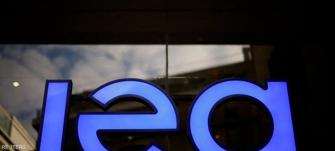 Close-up of a blue illuminated sign with the letters 'l', 'e', and 'a' visible against a dark background; Reuters watermark in the corner.