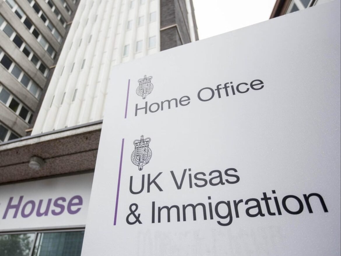 White government signboard reading 'Home Office' and 'UK Visas' with crests, placed in front of a modern office building exterior.