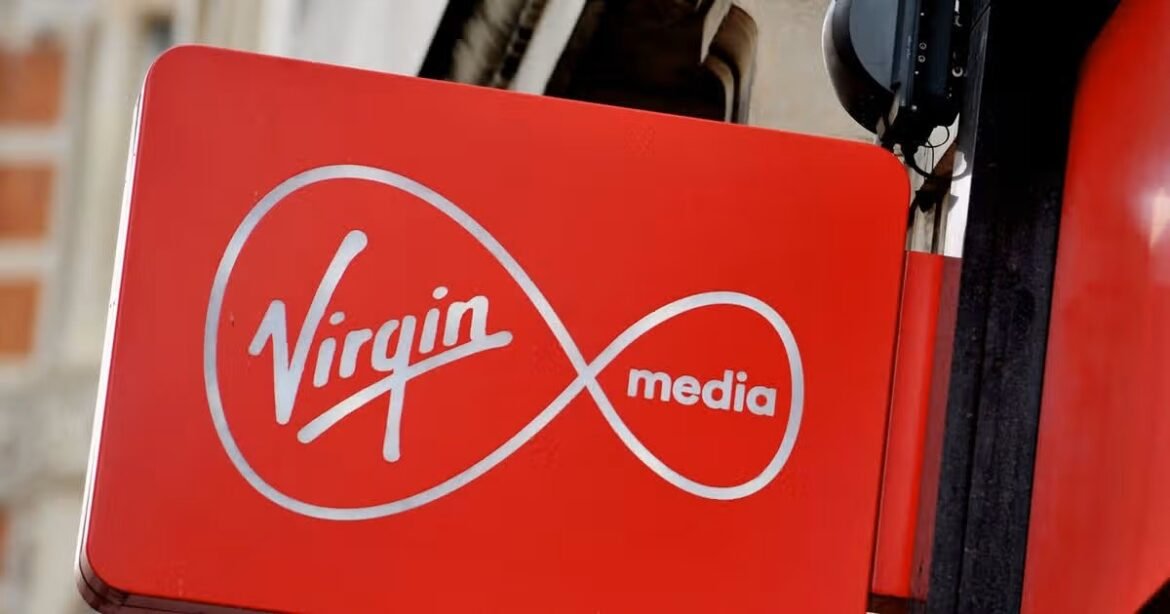 Virgin Media logo on a red panel outdoors, displaying the white infinity symbol and 'Virgin' text