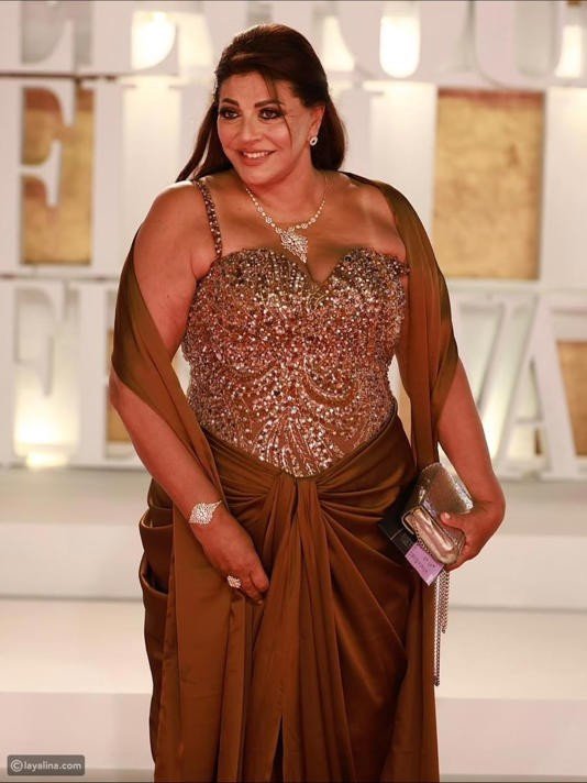 Woman in a Sparkling Bronze Evening Gown on a Red Carpet Holding a Silver Clutch  Aleumumnews