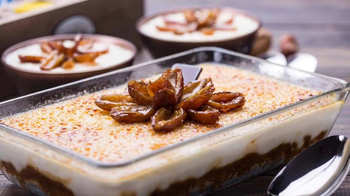 Layered creamy dessert in a glass dish topped with caramelized date slices and toasted nuts on top.