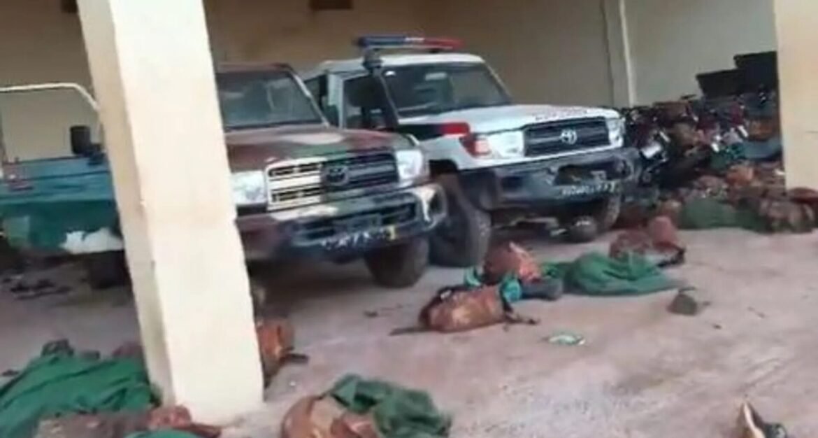 Two pickup trucks parked under a covered area, with green tarps on the ground and several bodies covered nearby.