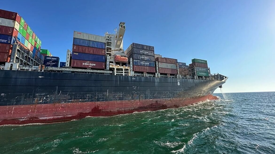 Large cargo ship with stacked colorful shipping containers on calm blue sea.