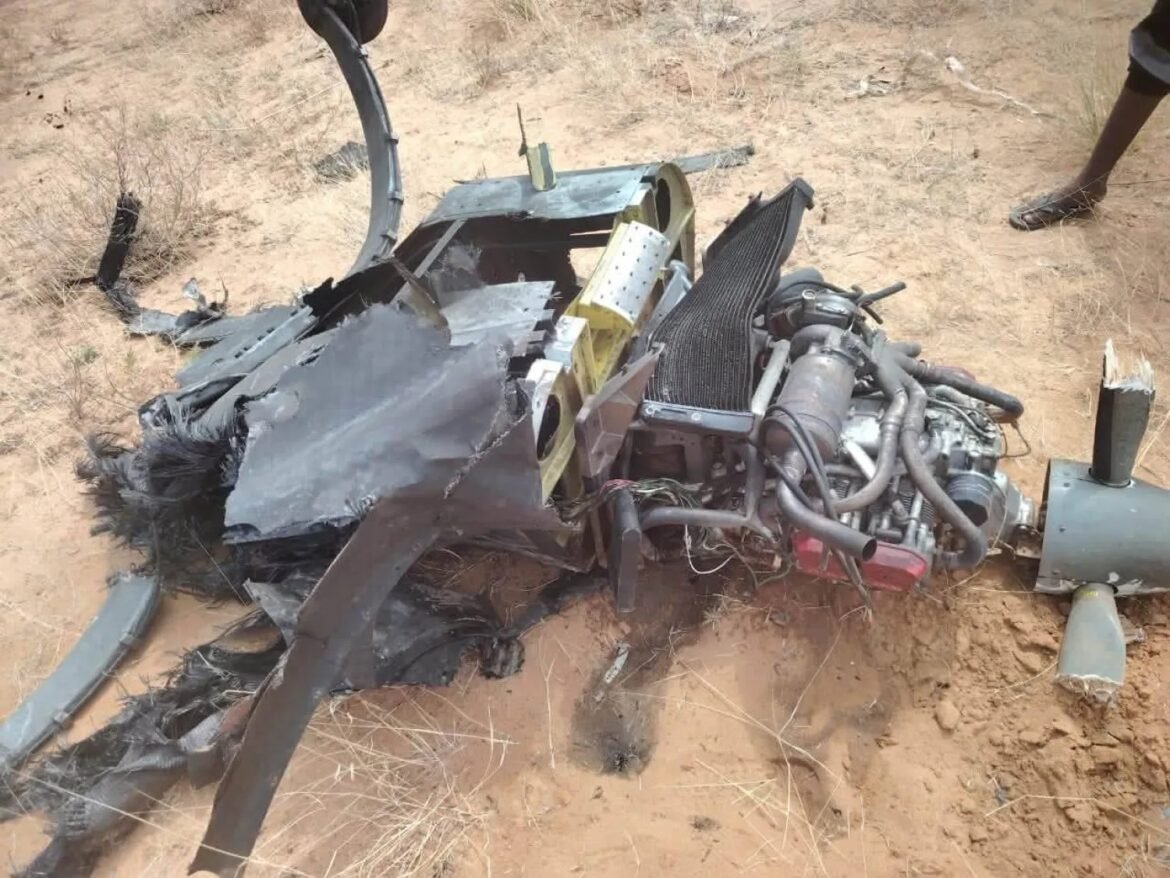 Wrecked aircraft wreckage on sandy ground, exposed engine, tangled metal panels and debris scattered nearby