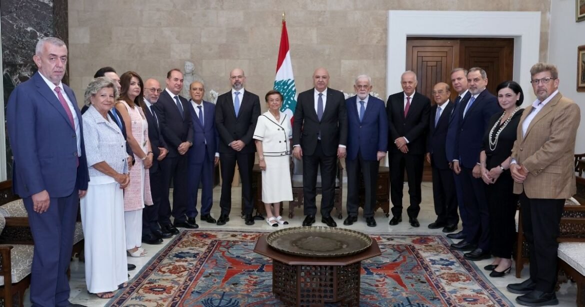 Group of formally dressed officials posing for a formal portrait in a room with a Lebanese flag in the background.
