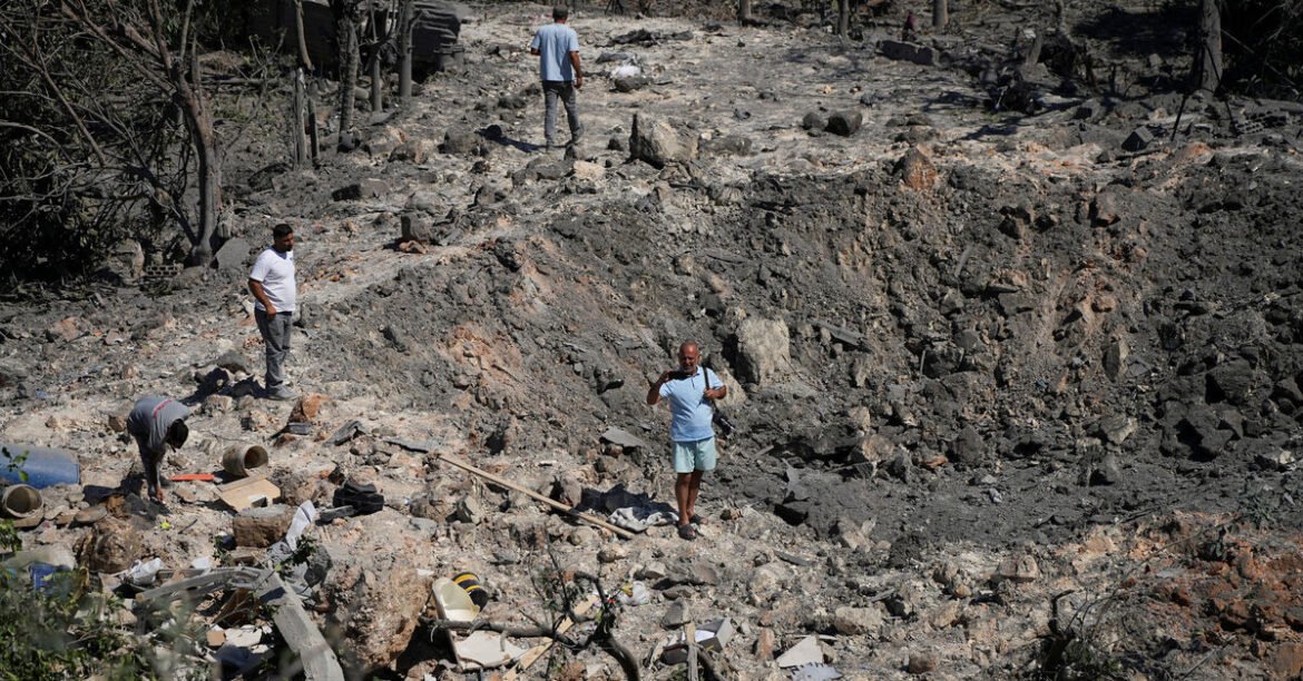 Group of men exploring a debris-strewn, burned landscape with rocks and charred vegetation.