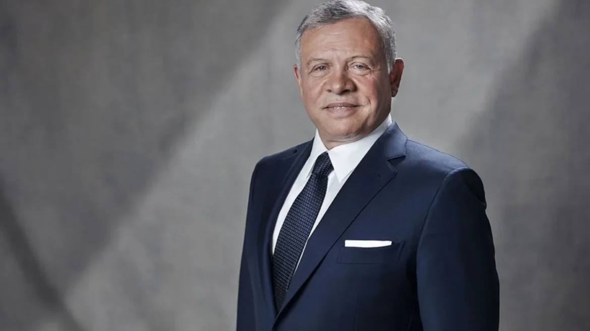 Professional head-and-shoulders portrait of a middle-aged man in a navy suit, white shirt, and patterned tie against a gray backdrop.