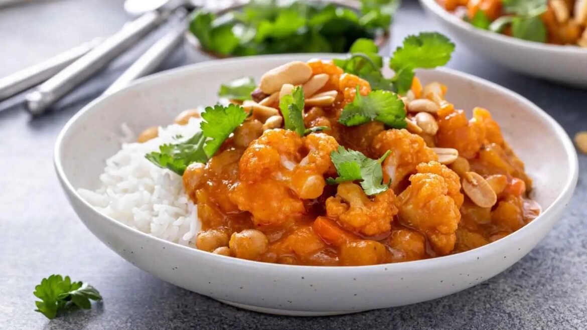 Orange-glazed chicken bites with white rice, topped with cilantro and peanuts in a shallow bowl