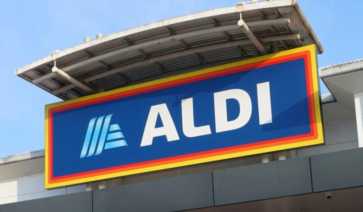 ALDI supermarket sign on a storefront with a blue background and yellow-red border under a clear sky on top of the building