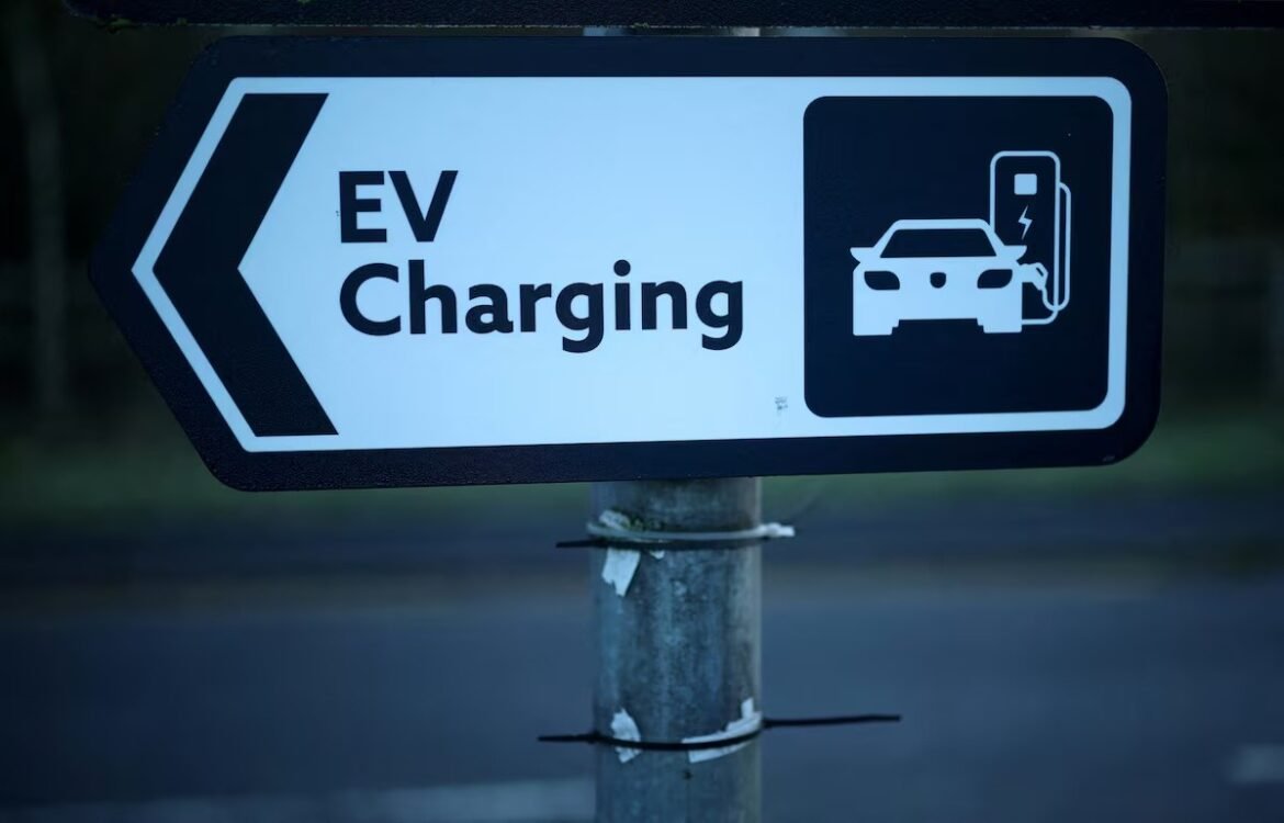 Left-pointing EV charging sign with a car charging illustration on a post