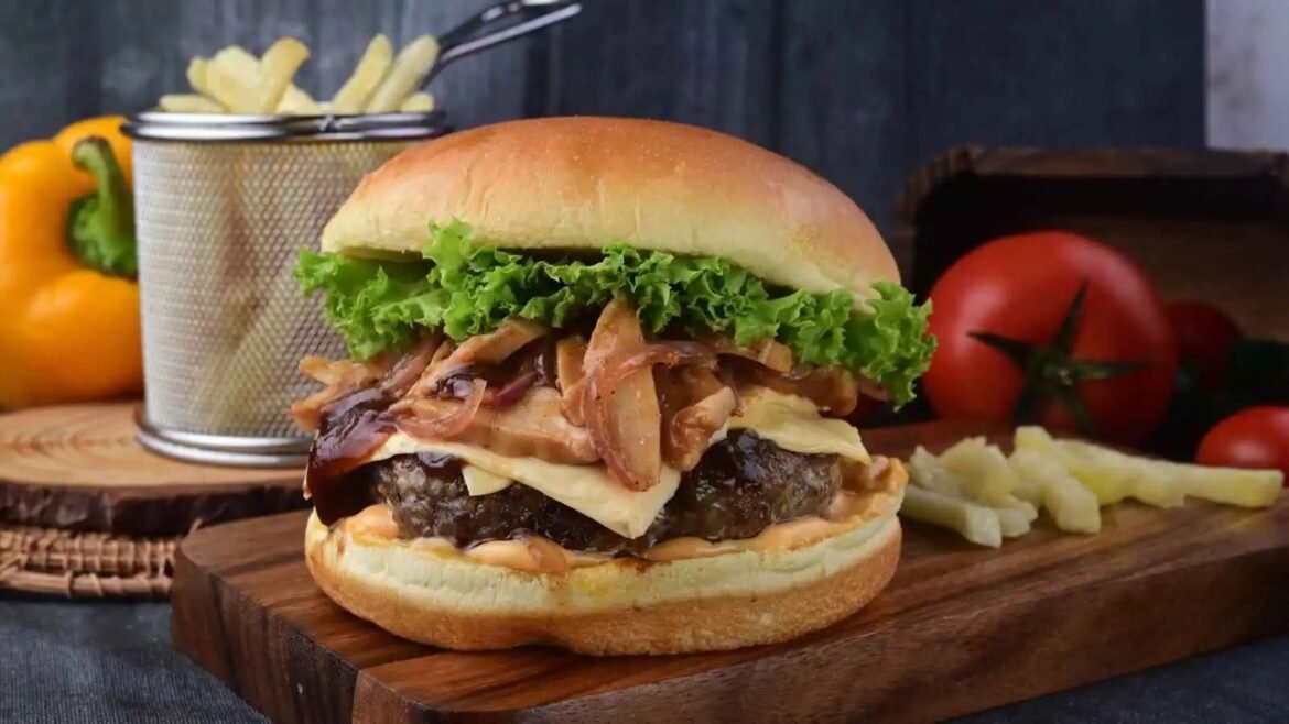 Juicy hamburger on a toasted bun with lettuce, caramelized onions, and melted cheese, served on a wooden board.