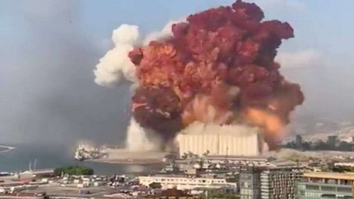 Massive explosion at a coastal power plant with a towering smoke plume and mushroom cloud over the city.