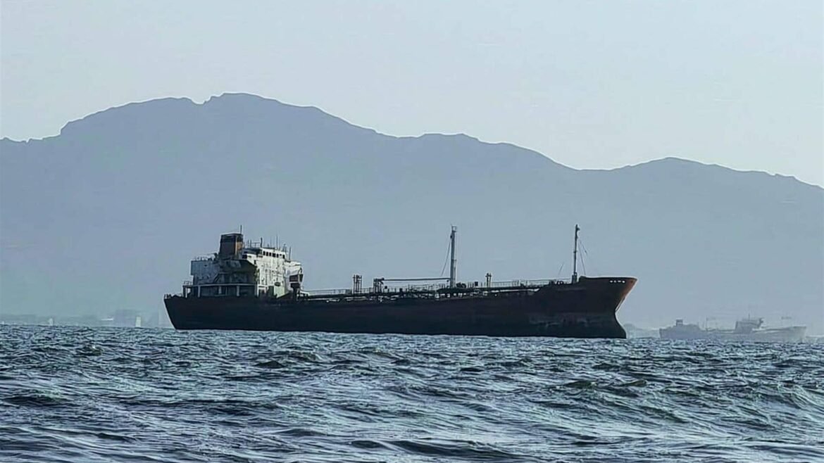 Cargo ship sailing on choppy water with hazy blue mountains in the background.