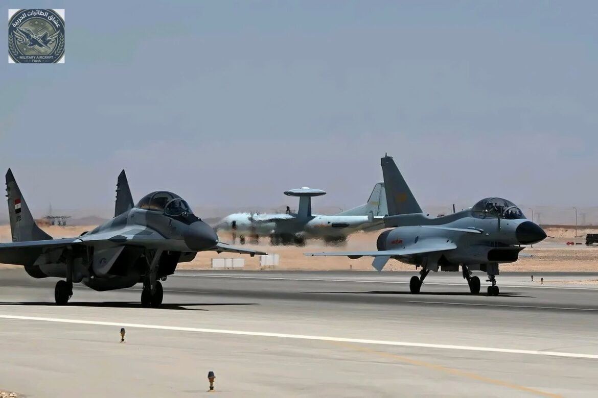 Two fighter jets taxiing on a runway with a desert airbase in the background.