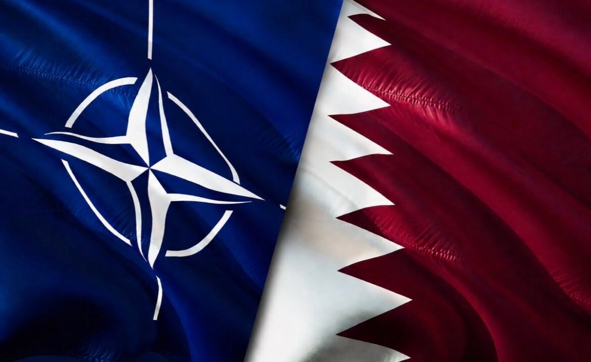 Two flags shown side by side: NATO emblem on a blue flag next to Qatar's maroon-and-white flag with a zigzag edge, suggesting a diplomatic context.