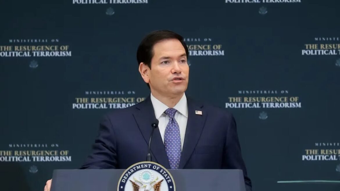 Man at a podium with the U.S. Department of State seal, speaking at a briefing about political terrorism.