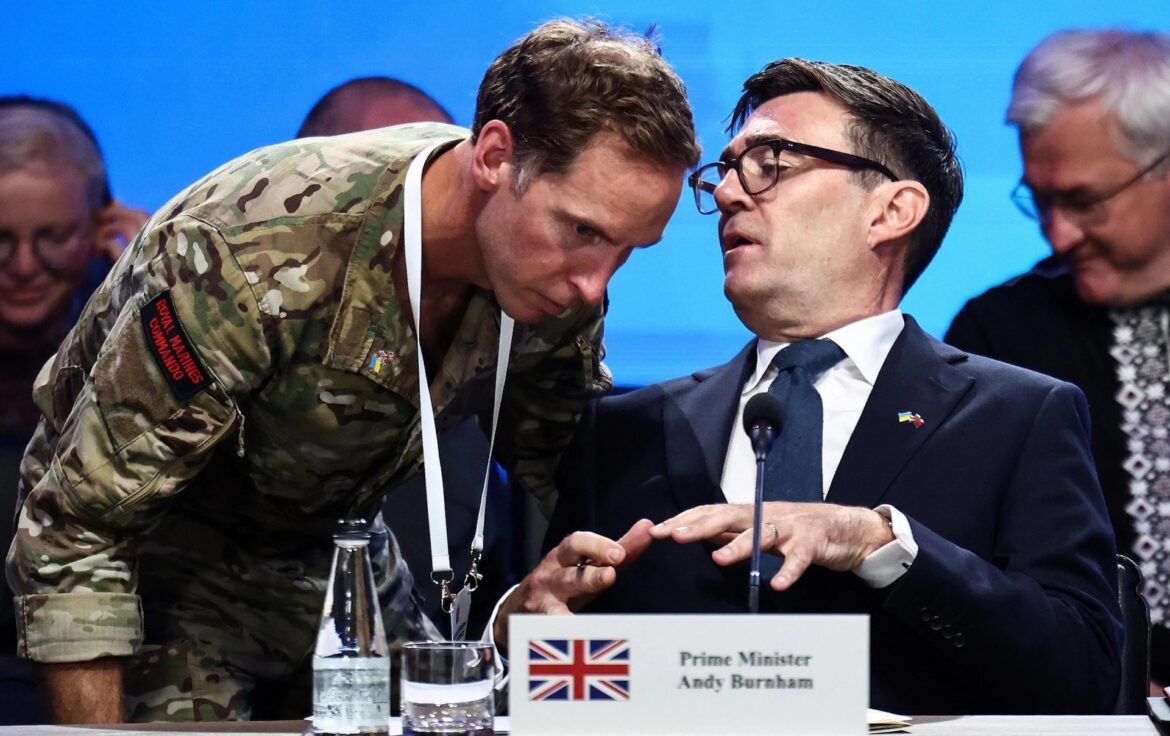 Military officer in camouflage leans in to speak with a suited man at a formal briefing, nameplate with UK flag visible in front.