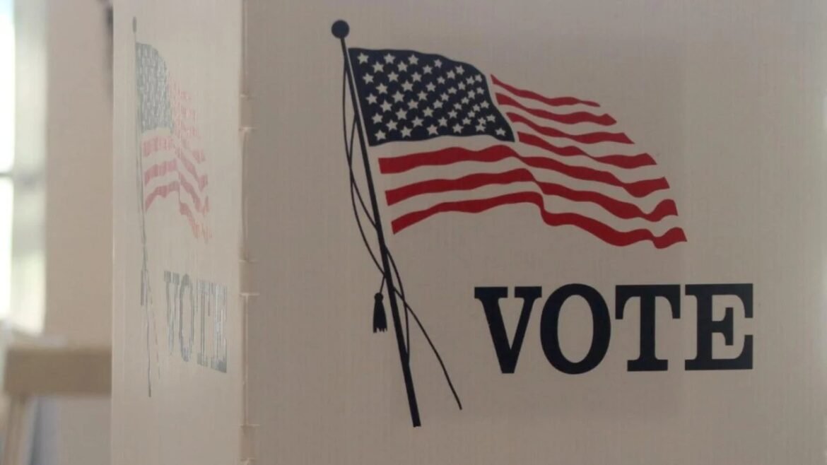 Voting booth with a waving American flag graphic and the word VOTE