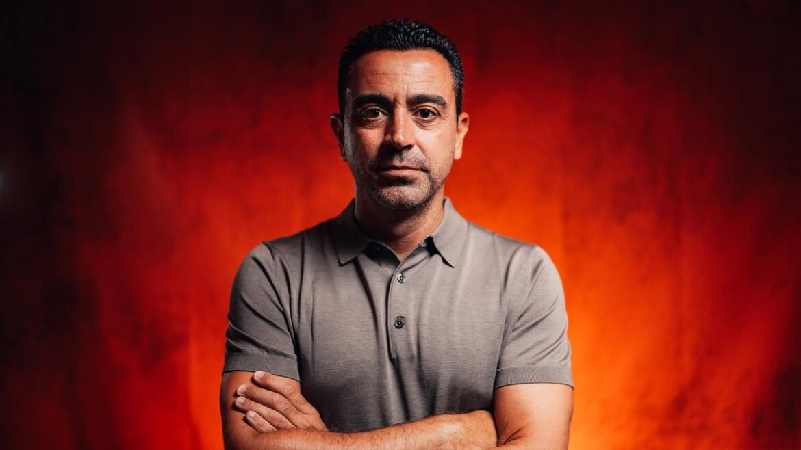 Portrait of a man with arms crossed, wearing a gray polo shirt, against a warm orange-red background.