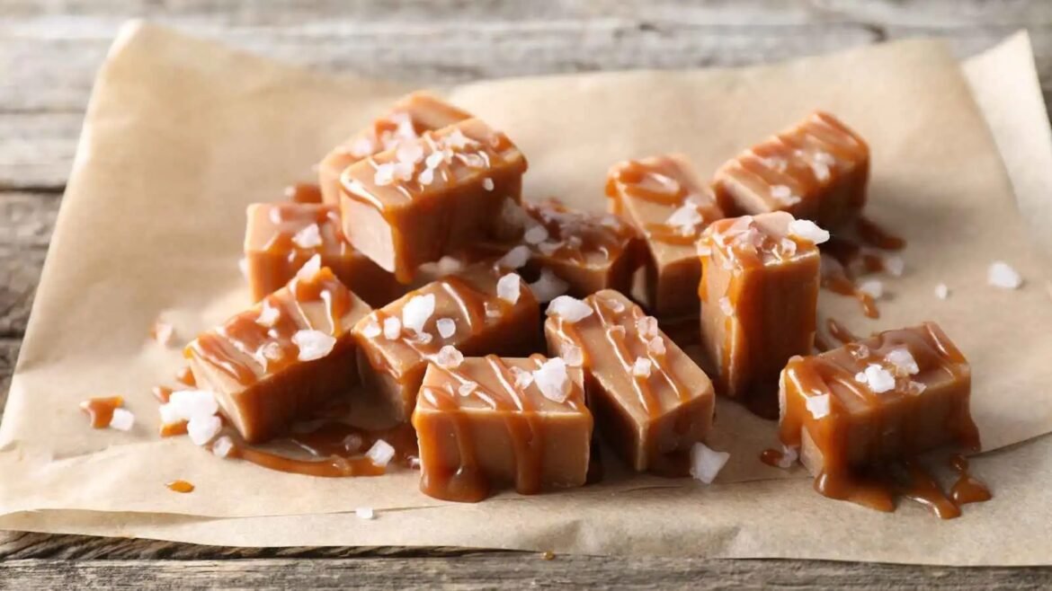 Caramel fudge cubes sprinkled with coarse sea salt on parchment paper.