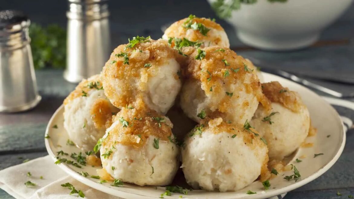 Pile of golden-brown, crumb-topped biscuits garnished with chopped parsley on a white plate.
