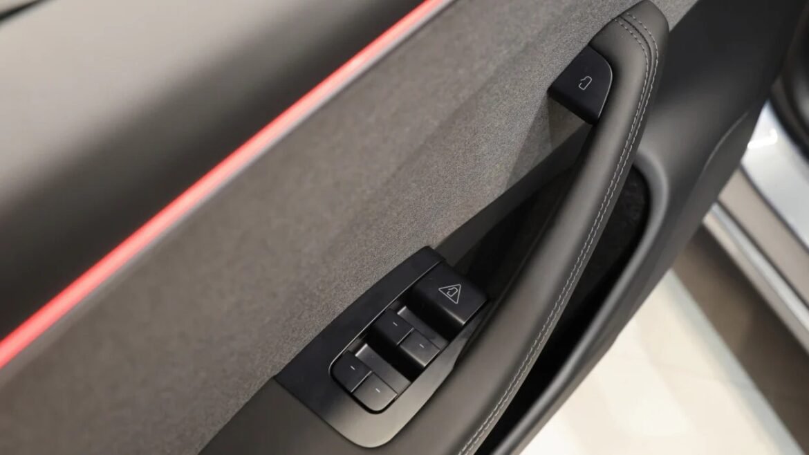 Close-up of a car door interior showing power window controls and a door handle on a gray panel.