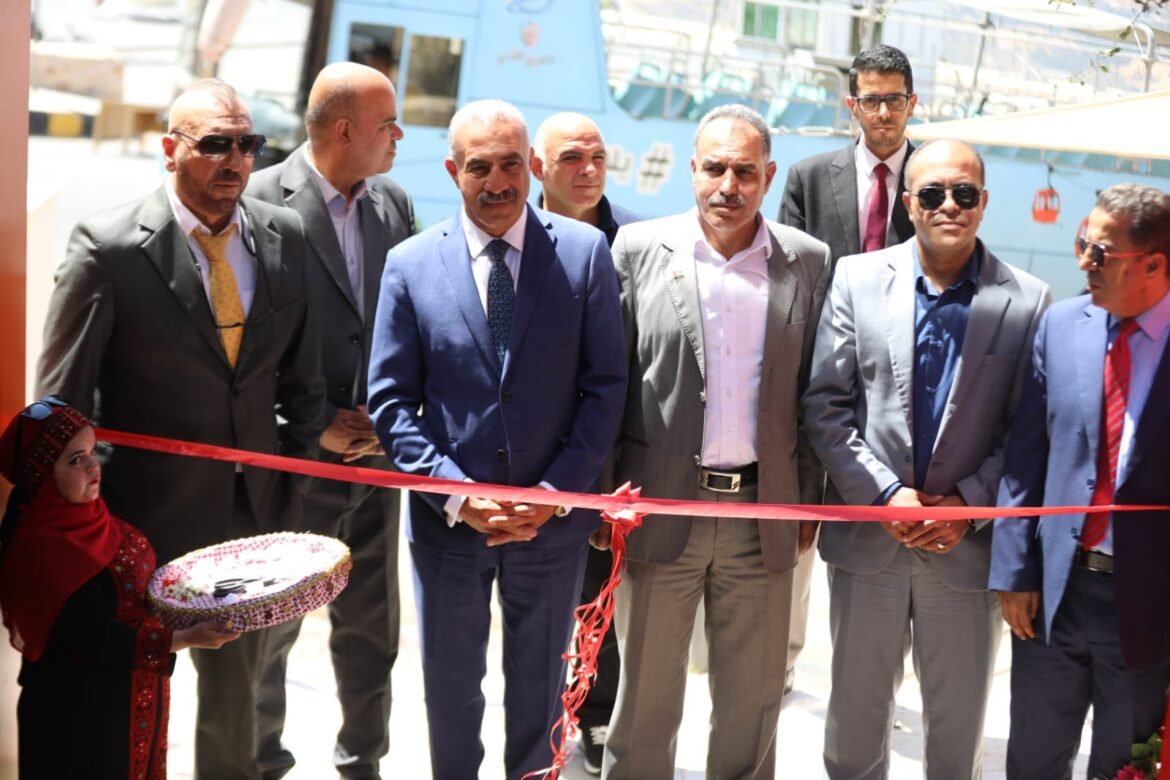 Group of formally dressed men at a ribbon-cutting ceremony, with a woman in traditional attire presenting a decorative basket in the foreground.