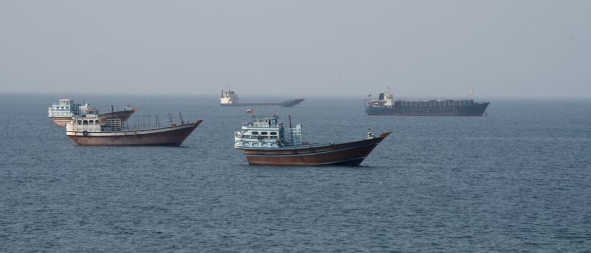 Several wooden fishing boats float on calm blue water, with a distant large cargo ship on the horizon.