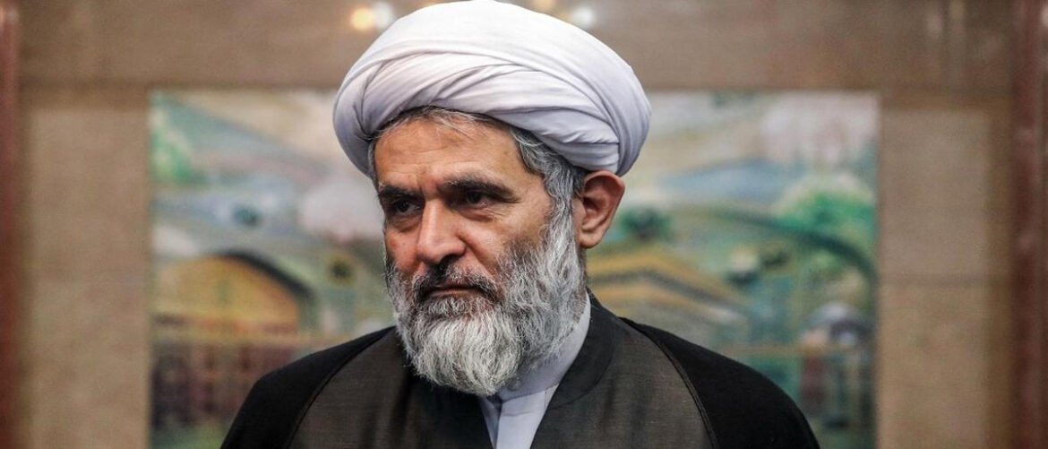 Religious cleric with a white turban and grey beard indoors, looking thoughtful.